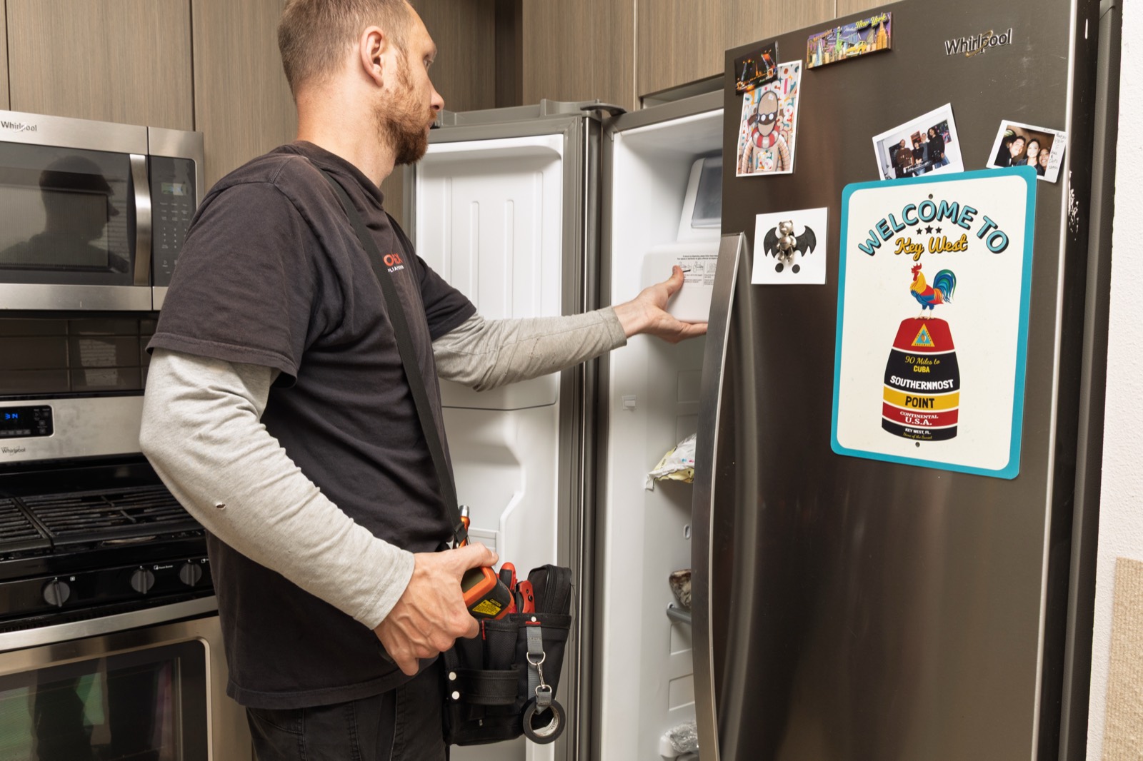 Fortex technician servicing a stainless side-by-side refrigerator in a kitchen